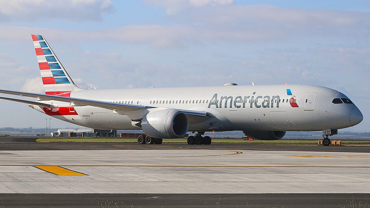 An American Airlines Boeing 787-9 Dreamliner in the airline's silver livery on the runway, seen side-on under a partly cloudy sky