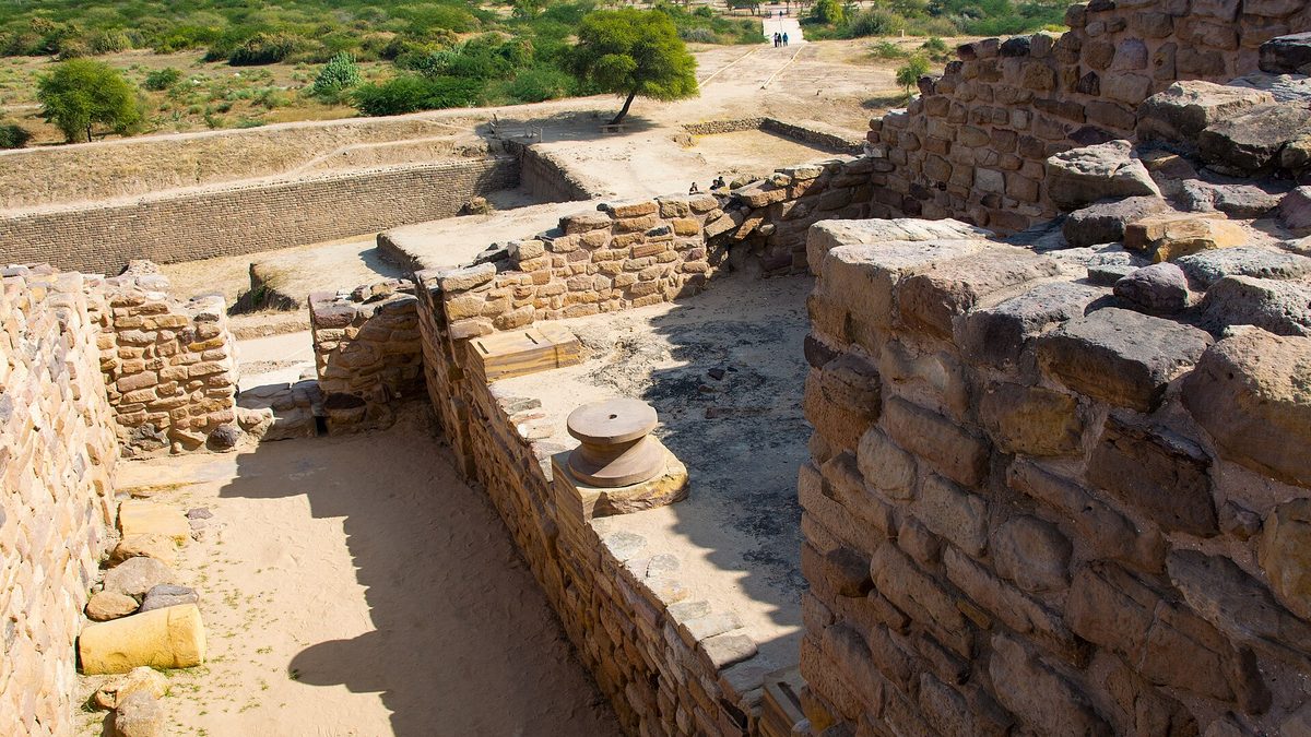 Stone walls and structures of the excavated Harappan city at Dholavira, with the wider archaeological site behind