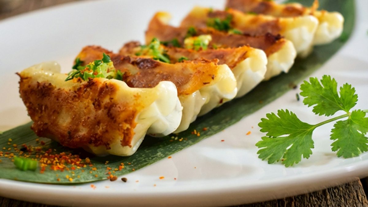 Golden pan-fried dumplings plated on a banana leaf with garnish