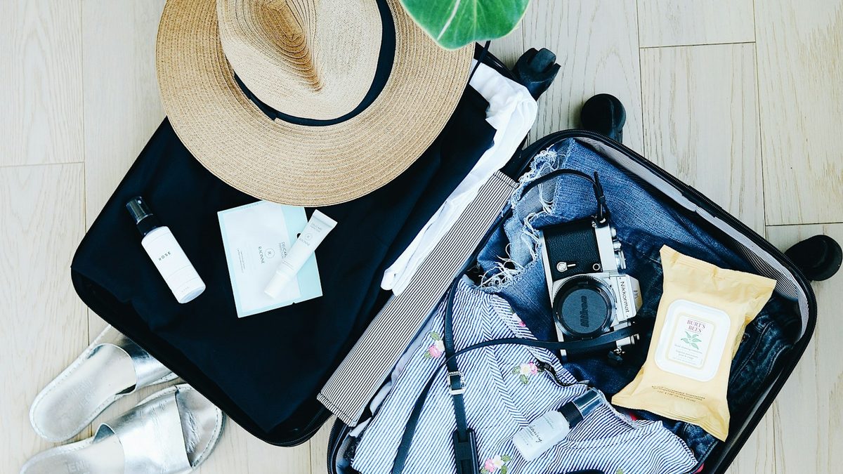 Open suitcase being packed with clothes and travel documents