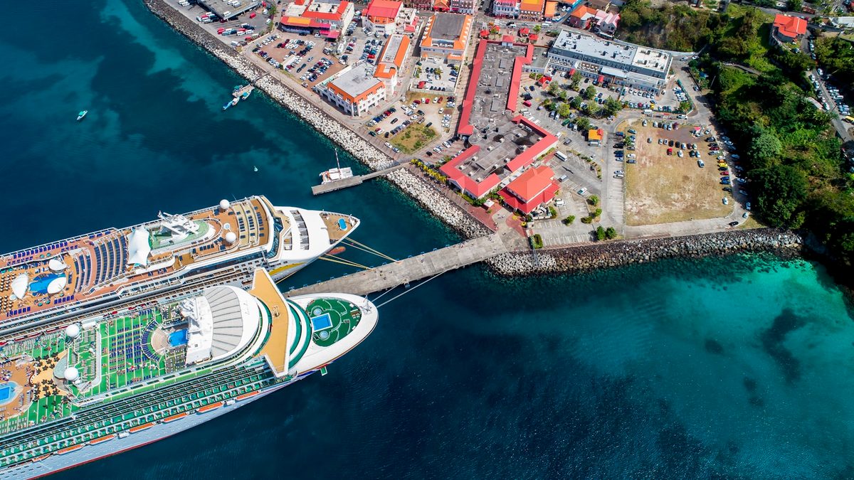 Aerial view of two cruise ships berthed alongside a Caribbean port town