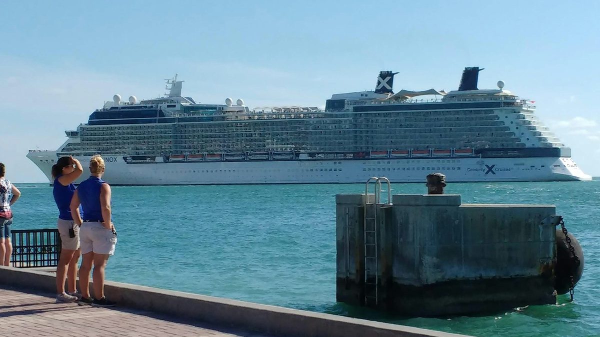 Celebrity Equinox at sea off Key West, watched by two people from the waterfront