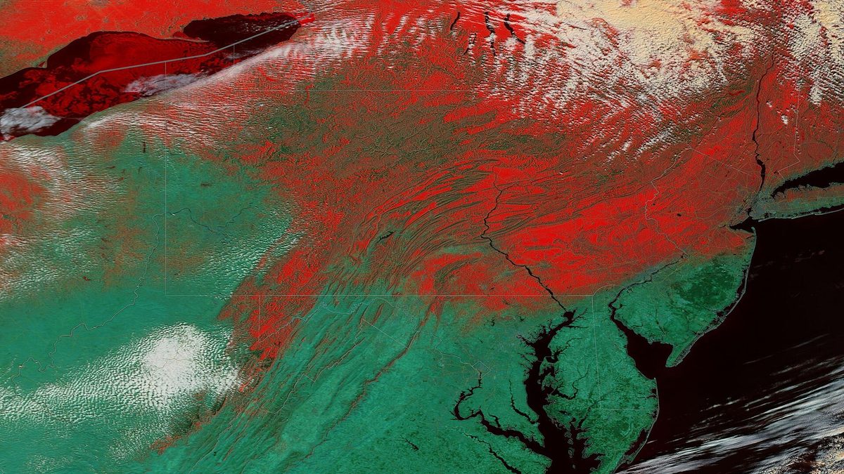 False-colour satellite view of the eastern United States in which snow appears bright red, showing a snow edge cutting diagonally across Pennsylvania, Maryland and West Virginia