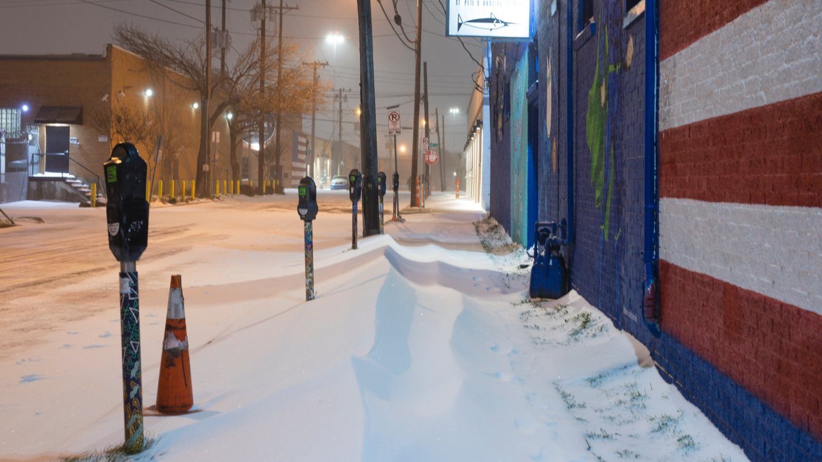 Snow drifted across a sidewalk and parking meters in the Deep Ellum district of Dallas during the February 2021 Texas winter storm